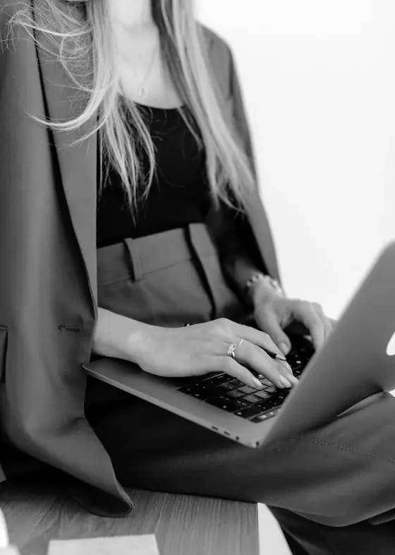 A person in business attire typing on a laptop computer.